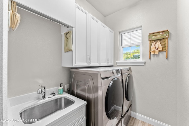 laundry area featuring sink, cabinets, separate washer and dryer, and light hardwood / wood-style floors