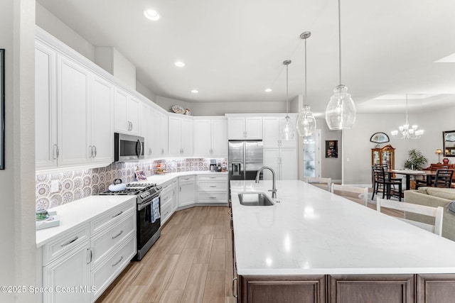 kitchen with sink, stainless steel appliances, a large island with sink, and white cabinetry