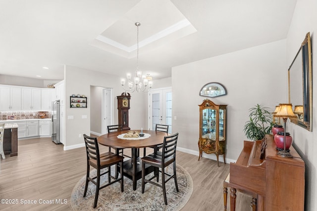 dining room featuring light hardwood / wood-style flooring, a raised ceiling, and a chandelier