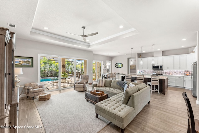 living room featuring ceiling fan and a raised ceiling