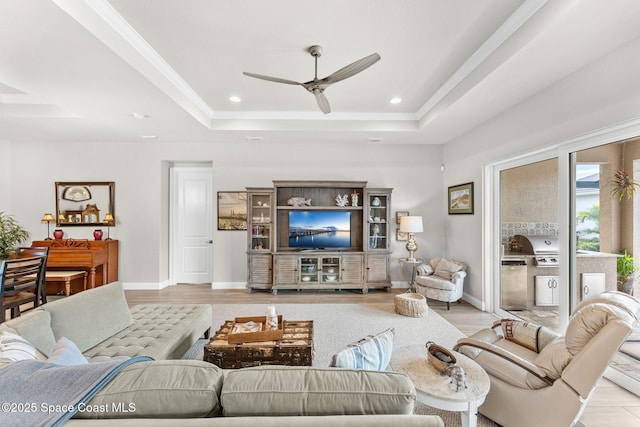 living room featuring ceiling fan, light wood-type flooring, and a raised ceiling