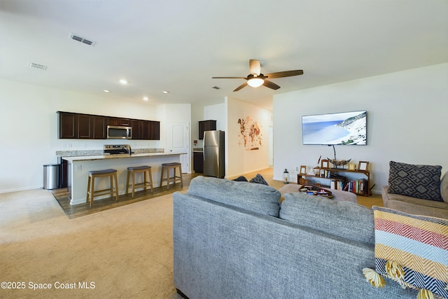 carpeted living room with ceiling fan