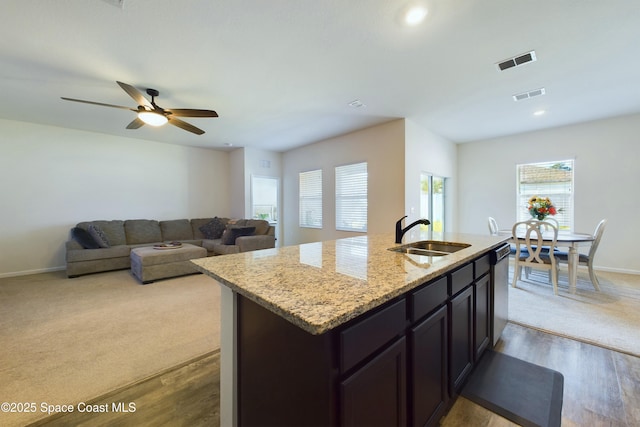 kitchen with a kitchen island with sink, sink, light colored carpet, and stainless steel dishwasher