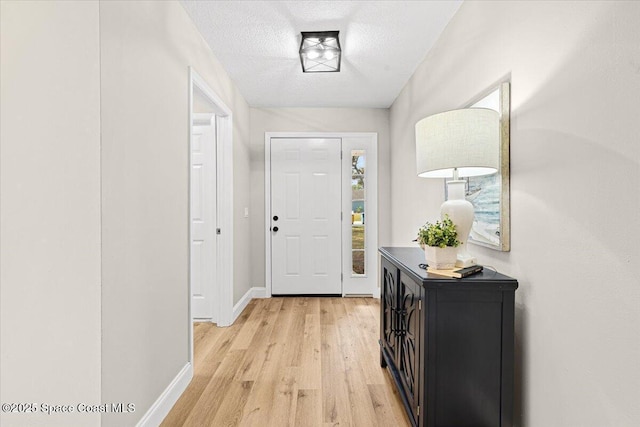 foyer entrance with a textured ceiling and light hardwood / wood-style flooring