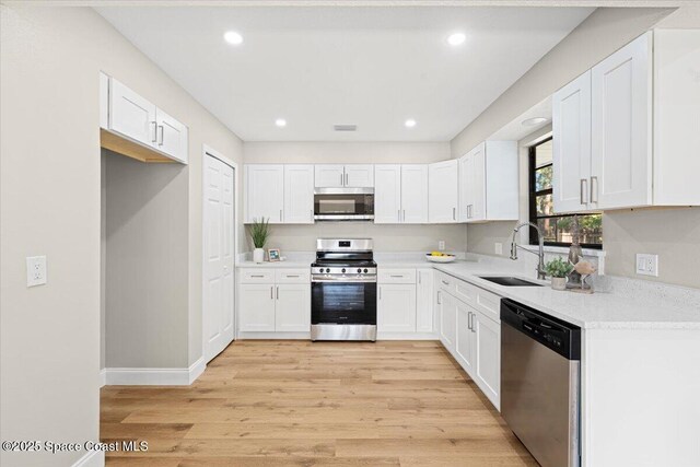 501 Empire Ave NE, Palm Bay, FL 32907 - kitchen with white cabinets, appliances with stainless steel finishes, light hardwood / wood-style floors, and sink