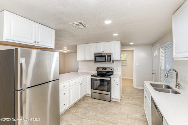 kitchen featuring sink, white cabinetry, stainless steel appliances, and a textured ceiling