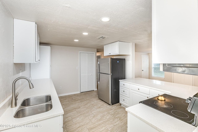 kitchen featuring sink, white cabinetry, stainless steel appliances, and a textured ceiling