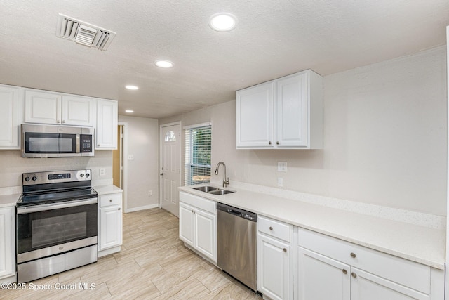 kitchen featuring sink, white cabinets, appliances with stainless steel finishes, and a textured ceiling