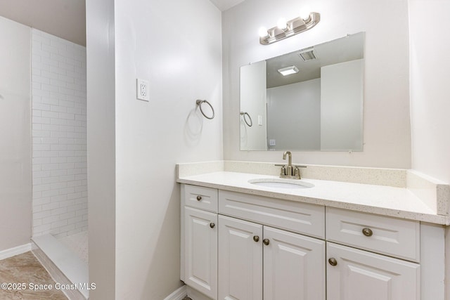 bathroom with vanity, a tile shower, and tile patterned flooring