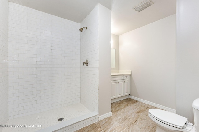 bathroom with vanity, toilet, and a tile shower