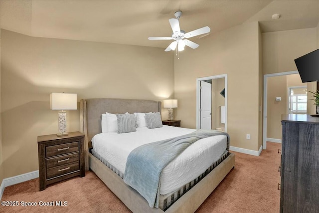 carpeted bedroom with ceiling fan, high vaulted ceiling, and ensuite bath