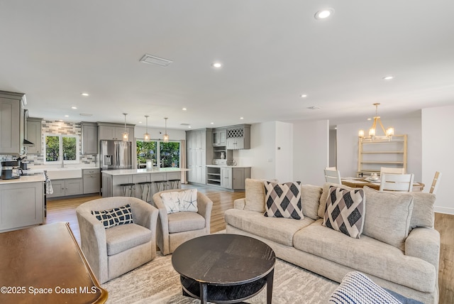 living room featuring a notable chandelier, light hardwood / wood-style floors, and sink