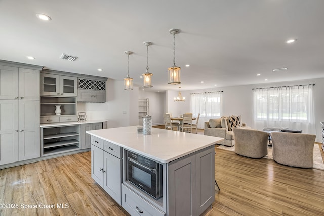 kitchen featuring a center island, light hardwood / wood-style floors, hanging light fixtures, and gray cabinetry