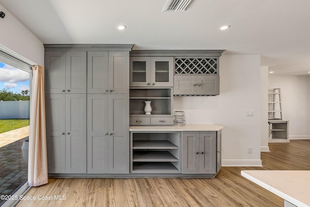 bar with gray cabinetry and light hardwood / wood-style floors