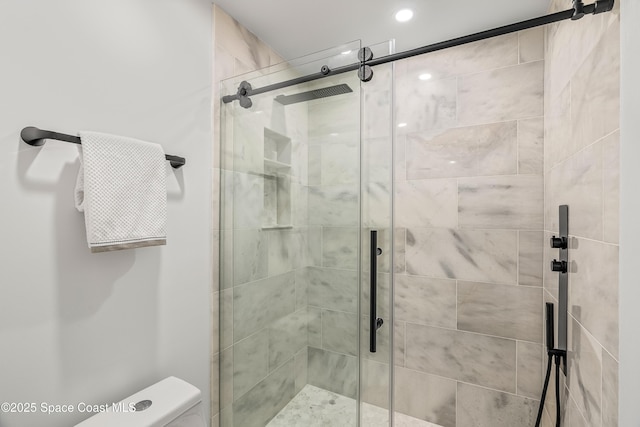 bathroom featuring a shower with door and toilet