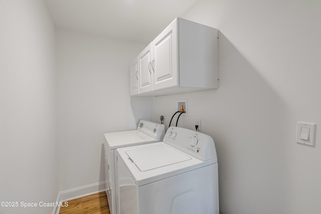 clothes washing area with cabinets, light wood-type flooring, and washing machine and dryer