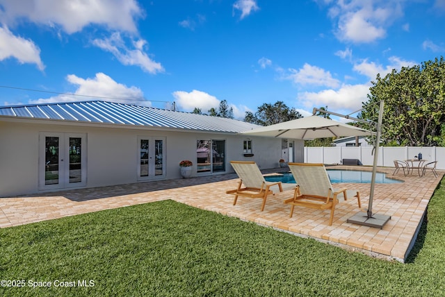 rear view of property with french doors, a fenced in pool, a patio area, and a lawn