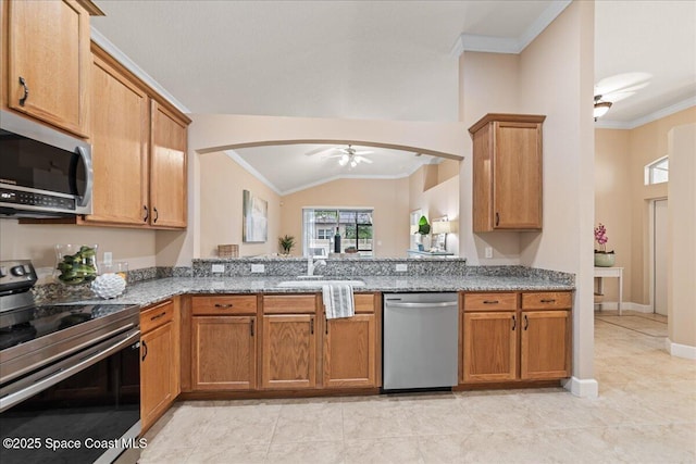 kitchen with vaulted ceiling, appliances with stainless steel finishes, stone counters, ceiling fan, and sink