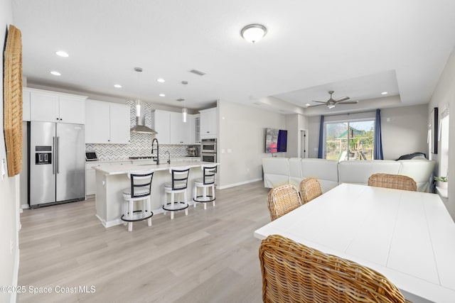 interior space featuring appliances with stainless steel finishes, decorative light fixtures, white cabinetry, and a raised ceiling