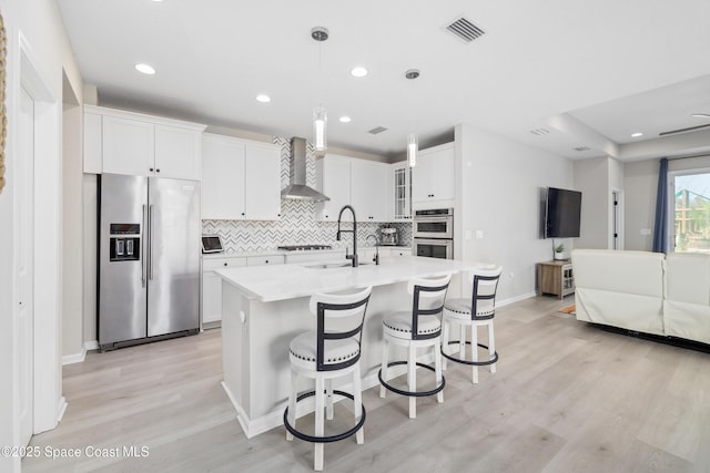 kitchen with sink, white cabinets, wall chimney range hood, and appliances with stainless steel finishes