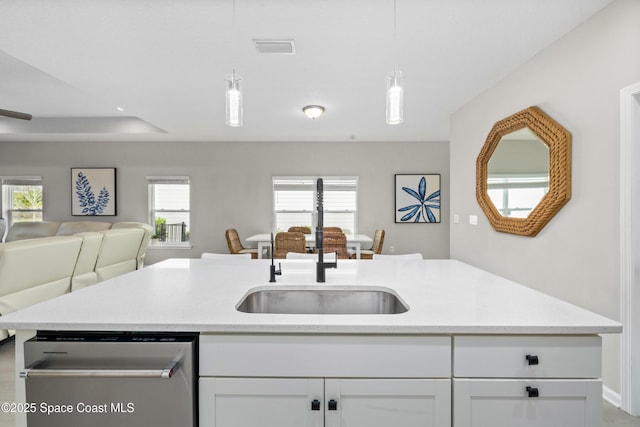 kitchen featuring stainless steel dishwasher, sink, white cabinets, and hanging light fixtures