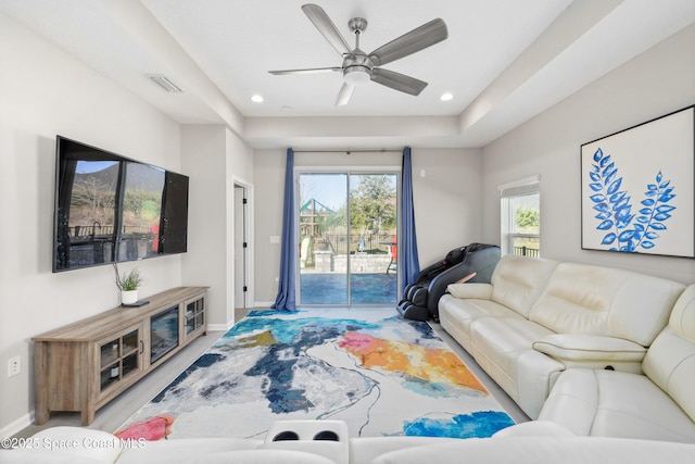 living room with a tray ceiling and ceiling fan