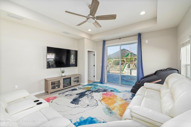 living room with ceiling fan and a tray ceiling