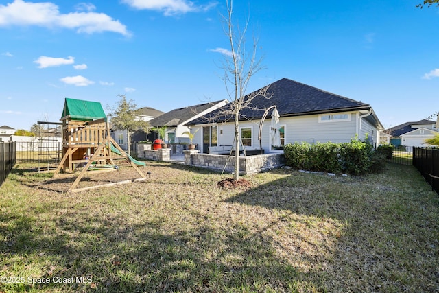 back of house with a yard and a playground