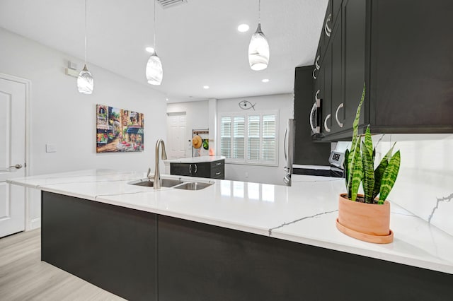 kitchen featuring decorative light fixtures, kitchen peninsula, and sink