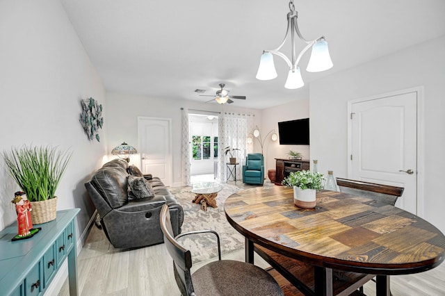 dining area with light hardwood / wood-style flooring and ceiling fan with notable chandelier