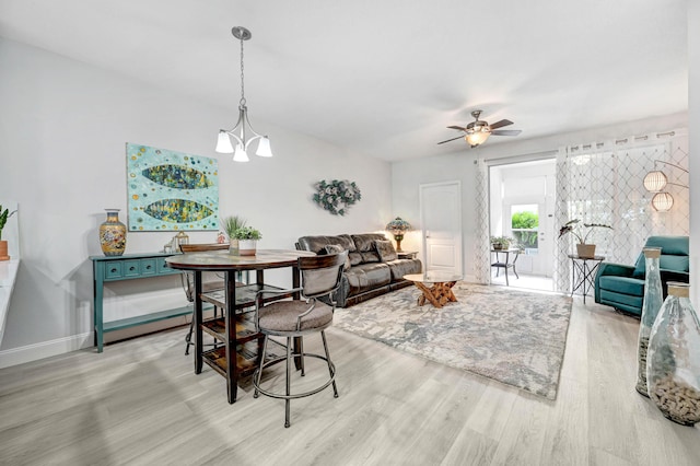 dining area with ceiling fan with notable chandelier and light hardwood / wood-style flooring