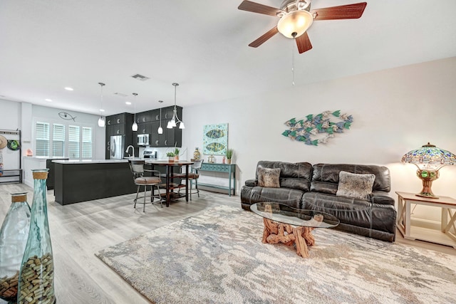 living room with ceiling fan and light hardwood / wood-style floors