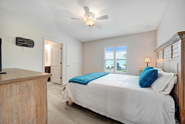 bedroom with ceiling fan, light wood-type flooring, ensuite bathroom, and a textured ceiling