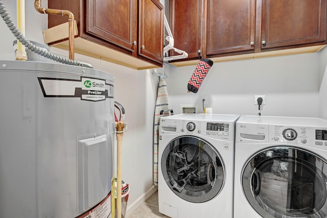 laundry area with electric water heater, washing machine and clothes dryer, and cabinets