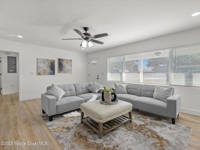 living room with electric panel, ceiling fan, and light hardwood / wood-style flooring