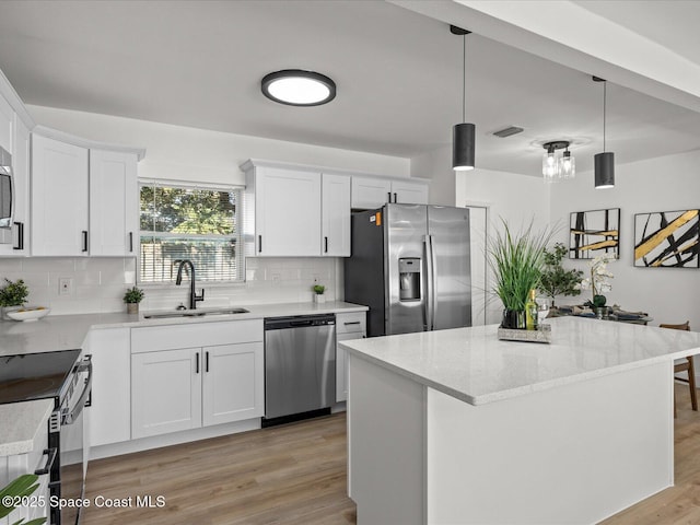 kitchen featuring white cabinetry, sink, stainless steel appliances, and decorative light fixtures