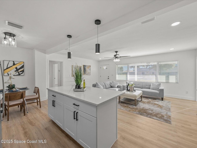 kitchen featuring light stone counters, light hardwood / wood-style flooring, hanging light fixtures, and ceiling fan