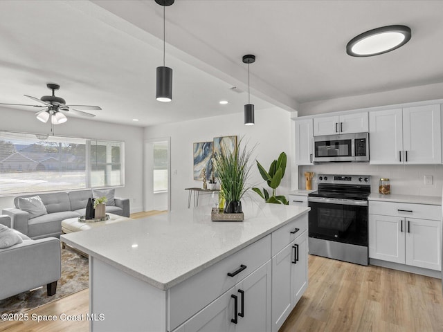 kitchen with white cabinets, appliances with stainless steel finishes, and decorative light fixtures