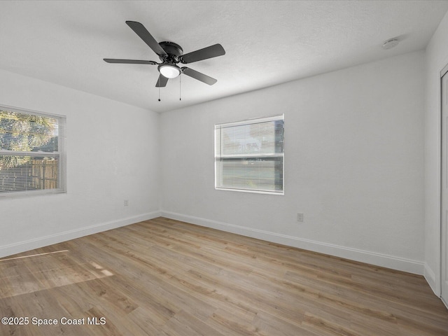 empty room featuring a wealth of natural light, light hardwood / wood-style flooring, and ceiling fan