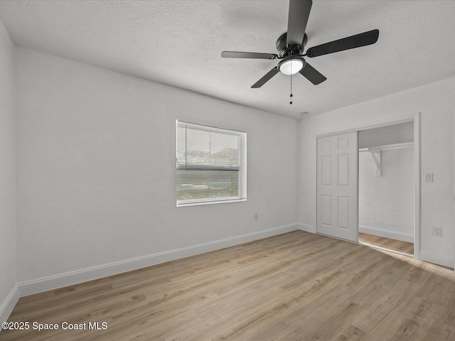 unfurnished bedroom with ceiling fan, a closet, a textured ceiling, and light hardwood / wood-style flooring