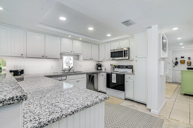 kitchen with white cabinets, sink, a tray ceiling, kitchen peninsula, and stainless steel appliances