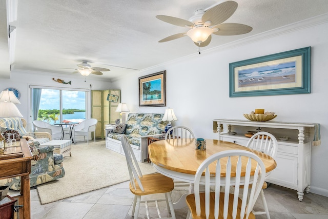 tiled dining room with ceiling fan, a textured ceiling, and ornamental molding