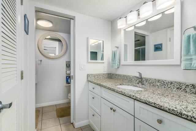 bathroom with walk in shower, tile patterned flooring, a textured ceiling, toilet, and vanity