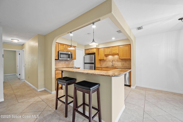 kitchen featuring decorative light fixtures, backsplash, a breakfast bar, and appliances with stainless steel finishes