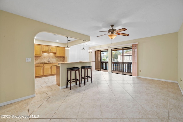 kitchen featuring a kitchen island, decorative backsplash, sink, hanging light fixtures, and light tile patterned floors