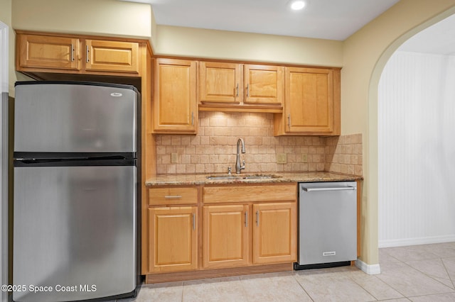 kitchen featuring sink, tasteful backsplash, light tile patterned floors, light stone countertops, and stainless steel appliances