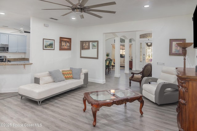 living room featuring ceiling fan, sink, and light hardwood / wood-style floors