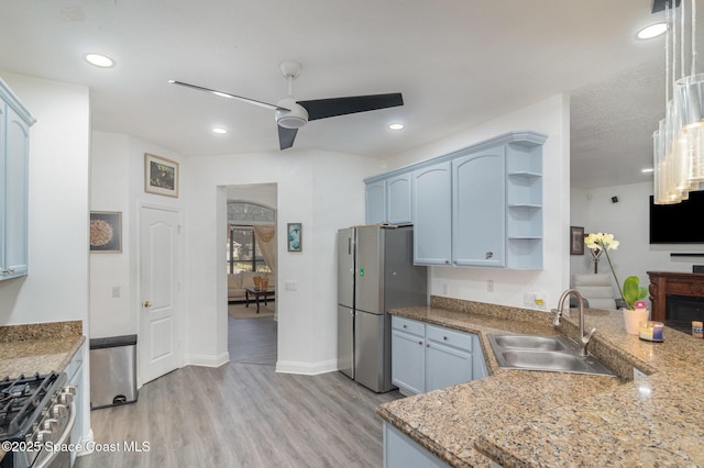 kitchen featuring appliances with stainless steel finishes, blue cabinetry, sink, ceiling fan, and light hardwood / wood-style flooring