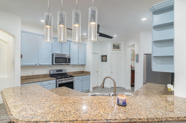 kitchen featuring pendant lighting, sink, light wood-type flooring, appliances with stainless steel finishes, and light stone counters