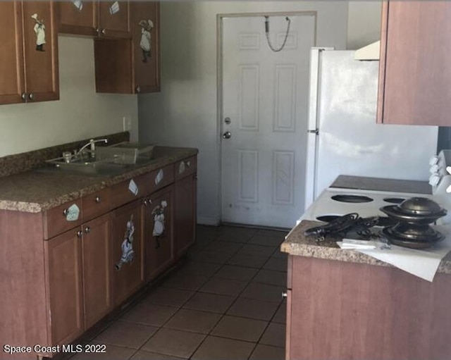 kitchen featuring white refrigerator, dark tile patterned flooring, and sink